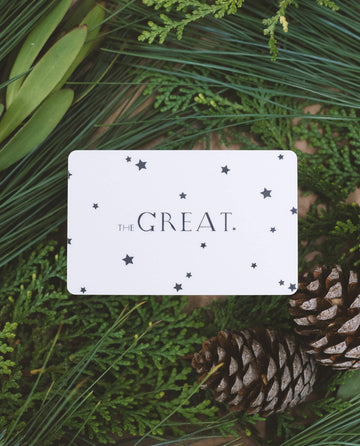 A Rise.ai Gift Card, adorned with the phrase "The Great" and star designs, is tucked among green foliage and pine cones, making it the ideal gift of choice.