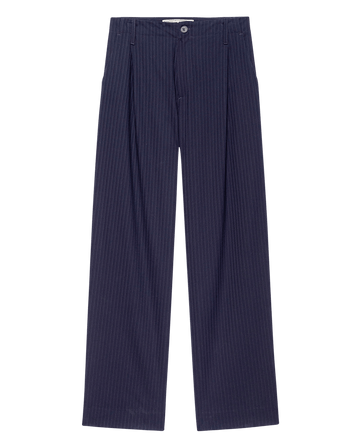 The Menswear Trouser in Dark Blue Stripe by THE GREAT. F25 COLLECTORS features a high-rise, wide-leg cut with front pleats, waistband, and side pockets, shown laid flat on a white background.