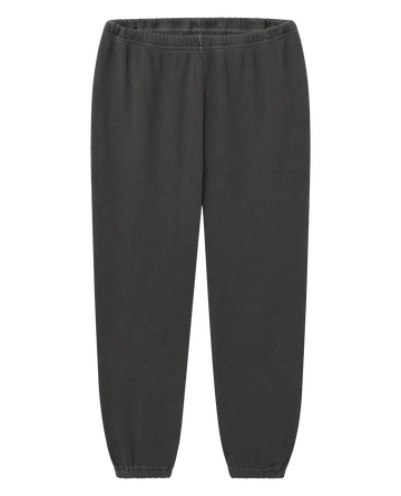 The Stadium Sweatpant in Washed Black by THE GREAT. CORE KNITS is a pair of vintage athletic sweatpants made from 100% cotton, featuring an elastic waistband and elastic cuffs at the ankles.