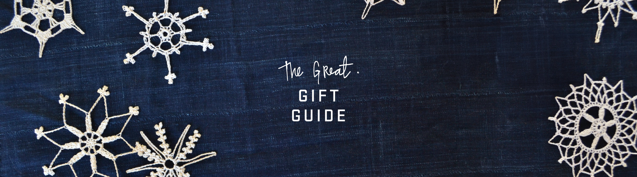 White crocheted snowflakes on a dark blue fabric background with the text "The Great. Gift Guide" in the center.
