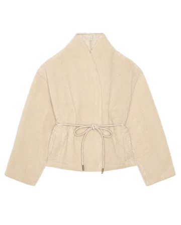 THE GREAT. H25 COLLECTION’s Reversible Drover Coat in Malt features beige faux shearling, a shawl collar, long sleeves, and a tie waist belt, shown laid flat on a white background.