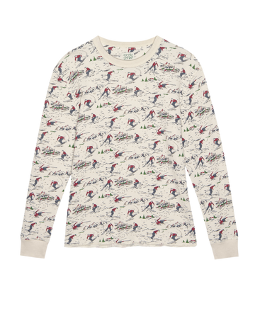 The Classic Crew Thermal – Slopeside Print by THE GREAT. F25 TGO is a cream crew neck with long sleeves, showcasing red and blue skiers and evergreen trees—ideal for layering on chilly days.