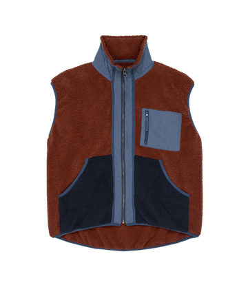 The Plush Tundra Vest by THE GREAT. F25 TGO in Chocolate & Navy features a sleeveless plush fleece design with a zipper front, blue trim, blue zip chest pocket, and two navy front pockets, inspired by vintage camping gear.