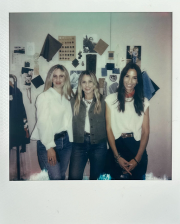 Three women stand side by side in front of a wall with various photos, fabric swatches, and materials displayed.