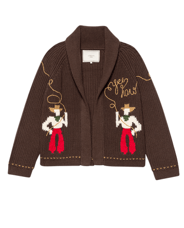 The Lasso Lodge Cardigan – Umber by THE GREAT. F25 COLLECTORS is a soft cotton-blend cowboy sweater with a shawl collar, featuring two lasso-wielding figures and “Yee Haw” on the front.