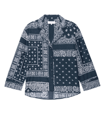 The Pajama Shirt – Bandana Patchwork by THE GREAT. F25 SLEEP features a blue and white long-sleeve button-up design with a spread collar and chest pocket, shown against a black background.