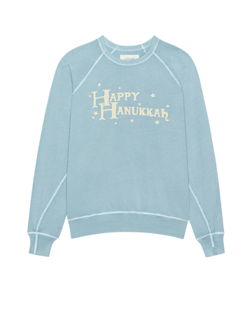 THE GREAT. H25 HOLIDAY GRAPHICS The College Sweatshirt in Confection Blue features a whimsical "Happy Hanukkah" graphic and stars—perfect for a cozy, collegiate look.