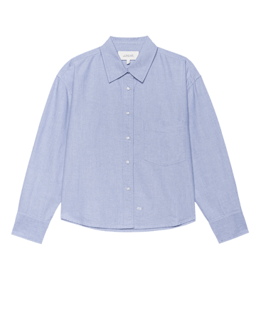 The Cropped Oxford Shirt in Classic Blue by THE GREAT. F25 D1 features long sleeves, a pointed collar, and a single chest pocket, shown against a plain background.
