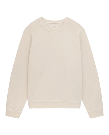 A plain, washed white crewneck vintage sweatshirt with long sleeves and a stitched V-neck detail at the collar, made in the USA from 100% cotton. This is The Slouch Sweatshirt by THE GREAT. CORE KNITS.