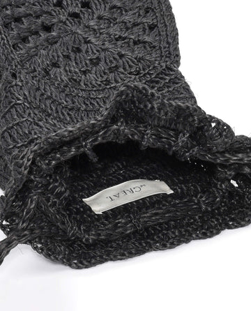 The Crochet Drawstring Bag in Black by THE GREAT. SU23 is shown open, with an inside white label visible, and is crafted from Agave plant fibers.