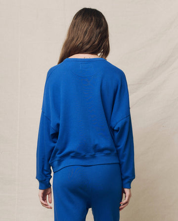 Someone wearing The Teammate Sweatshirt in Bright Cobalt by THE GREAT. SP25 KNITS, standing against a neutral backdrop.