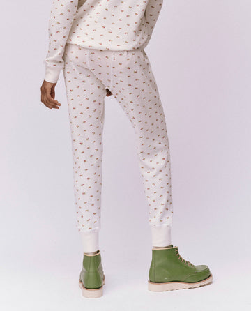 An individual wearing The Waffle Long John in White Mini Heirloom Rose by THE GREAT. HOL 24 ROSEBUD CAPSULE, complemented by green lace-up ankle boots, standing on a plain background.