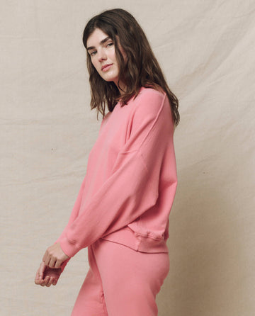 Against a beige background, a person casually wears The Teammate Sweatshirt in Solid -- Confetti by THE GREAT. SP25 KNITS with matching pants.