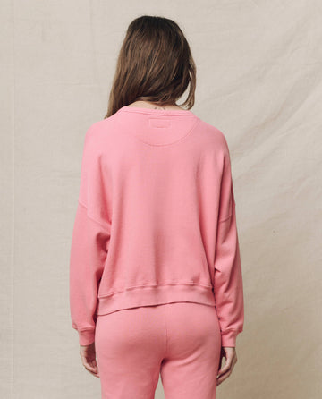 A person with long hair wears The Teammate Sweatshirt, Solid -- Confetti by THE GREAT. SP25 KNITS and sweatpants, facing away against a beige background.