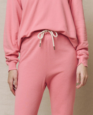 Wearing The Stadium Sweatpant in Confetti by THE GREAT. SP25 KNITS, someone stands effortlessly against a neutral background, showcasing the comfortable fit and drawstring waist paired with a pink sweatshirt.