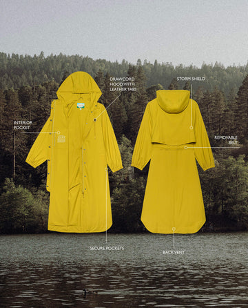 The Rain Trench – Sunshine by THE GREAT. SP25 TGO is shown over a forest and lake, highlighting its drawcord hood, storm shield, secure pockets, interior pocket, removable bill, and back vent.