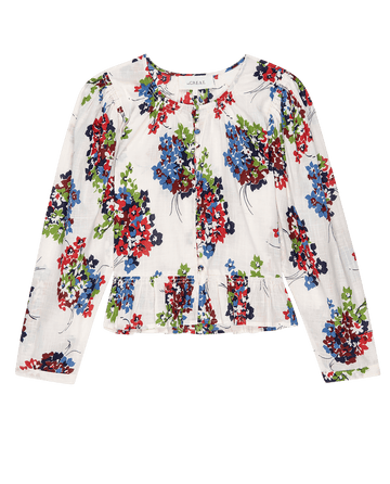 The Sicily Top by THE GREAT. PS25 is a fashion-forward Oasis Floral blouse, featuring a floral print with red, blue, and green flowers on a crisp white background and a round neckline.