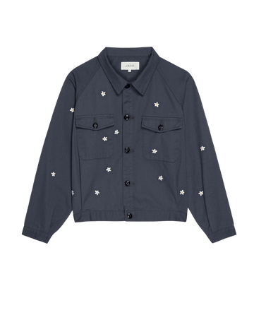 The Garage Jacket with Daisy Embroidery by THE GREAT. SP25 D2, in Blue Slate, has two chest pockets and delicate white daisies embroidered on a black background.