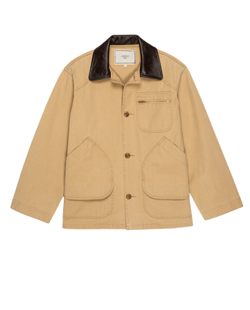 The Barn Jacket in Golden by THE GREAT. SP25 COLLECTORS is a tan button-up jacket with large front pockets, perfect for outdoor wear, featuring a stylish dark collar.
