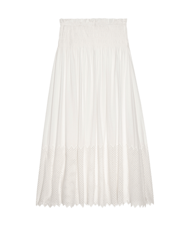 The Canary Skirt with Honeycomb Eyelet by THE GREAT. SP25 D2 is a white, knee-length skirt featuring a smocked waistband and honeycomb eyelet hem detail, presented against a plain background.