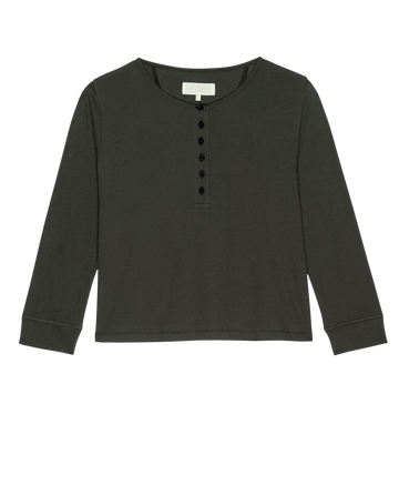 The Crop Sleep Henley by THE GREAT. FALL 24 SLEEP is a long-sleeved, washed black henley shirt featuring a round neckline and six black buttons on the front, crafted from cozy jersey fabric.