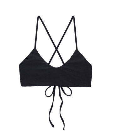 The Reversible Bralette by THE GREAT. SP25 SWIM features a black and leopard design, thin crisscross straps, a tie back closure, and a bralette-inspired silhouette, shown against a white background.