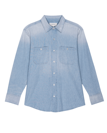 Introducing The Road Shirt in Riverbed Wash by THE GREAT. FALL 24 COLLECTORS: a light blue denim shirt with long sleeves, two front chest pockets, white buttons, vintage wash, and authentic workwear details, showcased against a plain background.