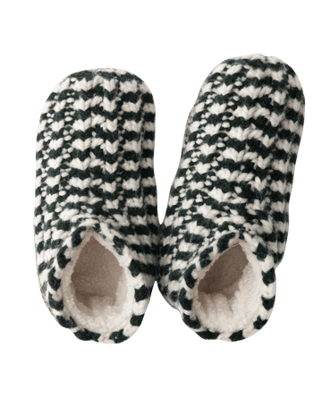 The Bootie Slipper by THE GREAT. HOL 24 SLEEP in a black and cream stripe design offers a chic look with its cozy sherpa lining, making it an ideal holiday gift for anyone seeking both comfort and style.