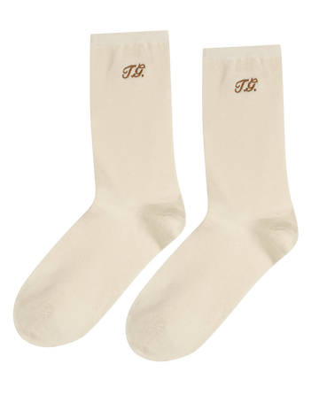 The Monogrammed Trouser Sock in cream by THE GREAT. F25 D1 ACCESSORIES features brown "TG" monogram on the upper sides.