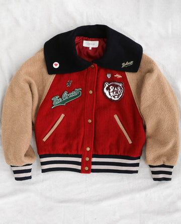 This wool varsity jacket showcases a striking design with a black collar, red body, and tan sleeves. It features embroidered patches of a tiger and "The Greats," along with other unique designs. You can personalize it further by adding collegiate-inspired flair with The Great Five Pack Enamel Pins from THE GREAT. HOL 22 ACCESSORIES to highlight its bold colors. The jacket is completed with a buttoned front, as well as striped cuffs and hem for that classic varsity look.