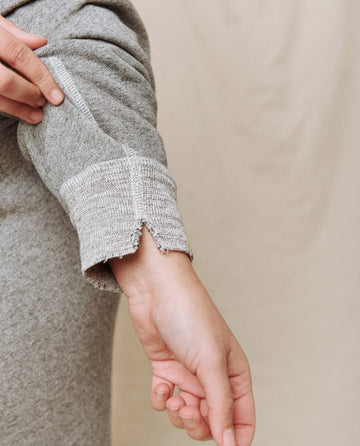 A hand adjusting the sleeve of The College Sweatshirt in Varsity Grey by THE GREAT. CORE KNITS.