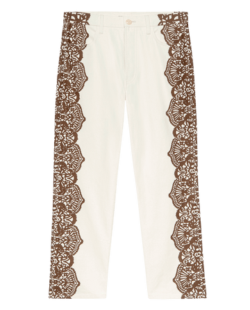 THE GREAT. F25 D1 The Lace Print Wayne Jean in cream with brown features canvas fabrication and wide western lace print panels along the outer sides, finished with a button and zip closure.