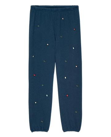 The Stadium Sweatpant by THE GREAT. PS26 features navy fabric with tossed floral embroidery, elastic waist and ankles, offering a vintage style and unique comfort. Made in Los Angeles.