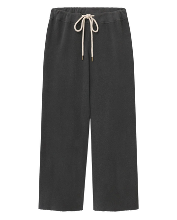 The Wide Leg Cropped Sweatpant in washed black by THE GREAT. CORE KNITS features a white drawstring waist and wide cropped legs, displayed against a white background.