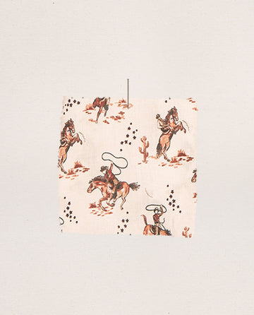 The Short Sleeve Pajama Shirt in Cream Cowboy by THE GREAT. SP25 SLEEP features a lively cowboy and horse print with riders, lassos, cacti, and stars on a light background—great for crafting unique sleepwear or a fun pajama shirt.