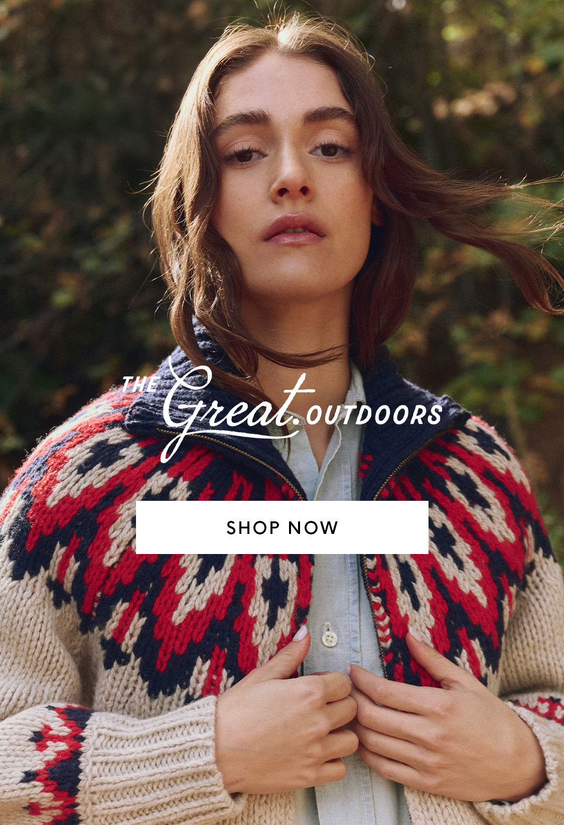 A woman wears a patterned knit sweater over a button-down shirt, standing outdoors with greenery in the background. Text reads: “The Great Outdoors. Shop Now.”.