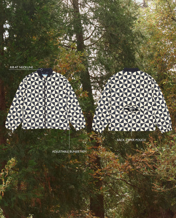 Two The Alps Puffer Jackets in Quilted Vintage Navy by THE GREAT. F25 TGO, made with recycled polyester, display front and back views against a forest, featuring ribbed neckline, adjustable bungee hem, and back zipper pouch.