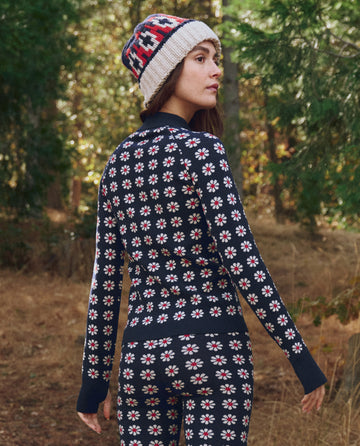 Wearing THE GREAT. F25 TGO’s Merino Quarter Zip in Frosted Daisy, this person pairs the slim, flower-patterned sweater with leggings and a knit hat, creating a chic look for the outdoors.