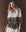 A woman with long blonde hair wears THE GREAT. F25 D1's The Chariot Top in cream with Western lace print, paired with a red neck scarf, standing against a brown background.