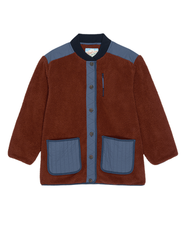 The Plush Tundra Jacket by THE GREAT. F25 TGO features chocolate fleece with navy accents on the shoulders, collar, pockets, and button placket, a front button closure, and multiple pockets inspired by vintage camping gear.