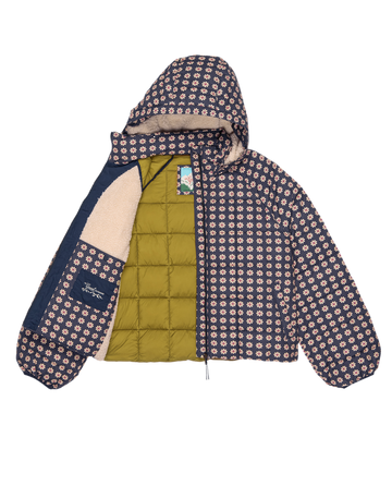The Whistler Puffer by THE GREAT. F25 TGO in Mini Frosted Daisy features a navy and pink geometric design, partially unzipped to show olive green quilted lining and tan fleece. Recycled insulation adds warmth, making it a stylish layering piece.
