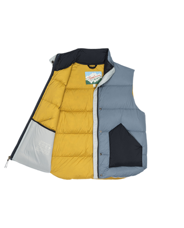 THE GREAT. F25 TGO Polar Vest – Navy Colorblock features yellow, blue, and black panels, shown partially unzipped to reveal its interior lining, brand label, and warm PrimaLoft insulation.