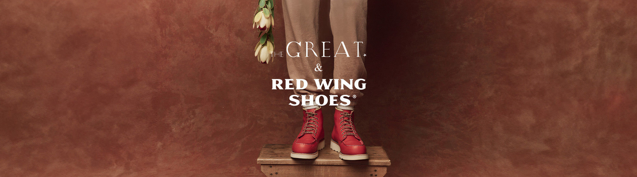 Person wearing red boots stands on a wooden stool, holding tulips. Text reads: THE GREAT. & RED WING SHOES.