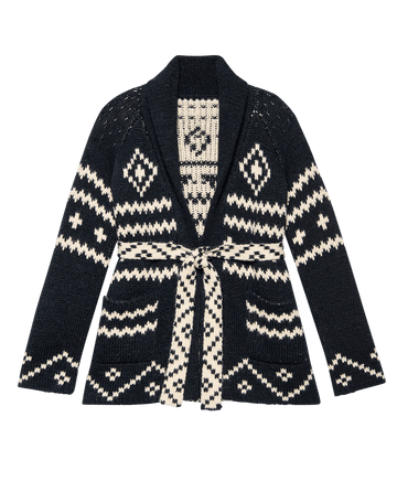 The Reversible Shepherd Cardigan by THE GREAT. F25 D1 features navy and cream jacquard with geometric patterns, front pockets, a shawl collar, and a matching belt.