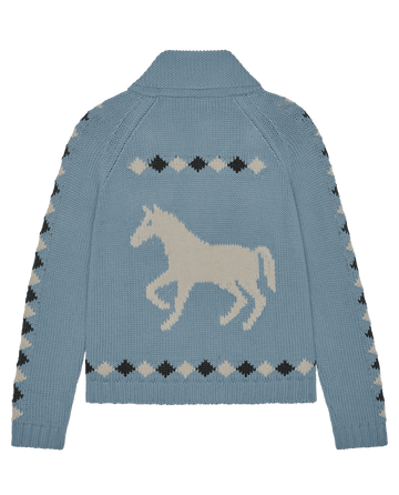 The Stable Lodge Cardigan by THE GREAT. in Blue Bell: a light blue cotton alpaca knit with a bold western horse motif on the back, and black and beige diamond patterns on the sleeves, shoulders, and hem.