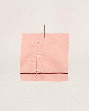 A square piece of rose bloom fabric with three white buttons and a horizontal dark line near the bottom, resembling THE GREAT. SP25 SLEEP's The Western Sleep Cami, displayed on a plain background.
