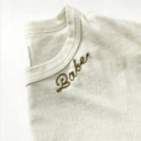 Close-up of a white t-shirt with the word "Babe" embroidered in cursive on the chest area.