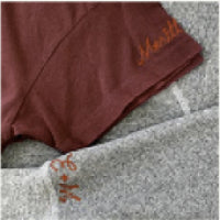 Close-up of two folded fabric items: one is maroon and the other is gray, both with cursive text stitched in orange.