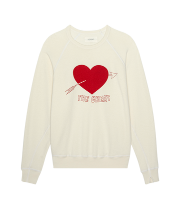 The College Sweatshirt by THE GREAT. PS26 features a washed white design with a bold red heart graphic and "THE GREAT" printed below.