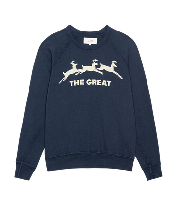 The College Sweatshirt by THE GREAT. H25 HOLIDAY GRAPHICS features a navy color with three white deer silhouettes and "THE GREAT" printed on the front.